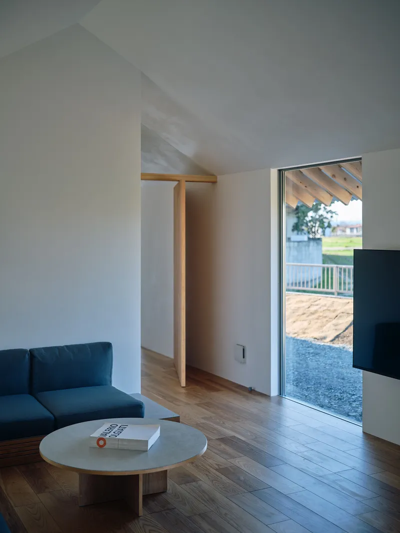 Living room with vaulted ceiling and timber column framing a doorway to the landscape beyond