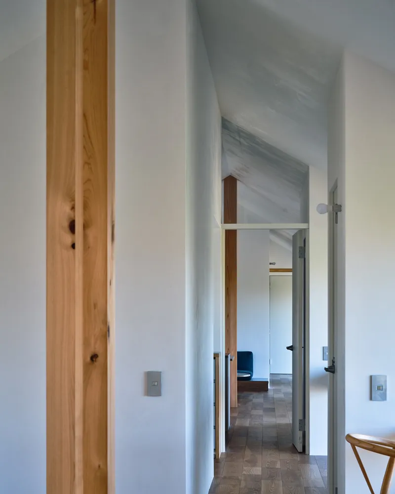 Hallway with exposed timber post beside doorways leading through white-walled rooms with vaulted ceilings