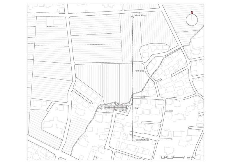 Site plan drawing showing the elongated building footprint among farm plots and residential fabric