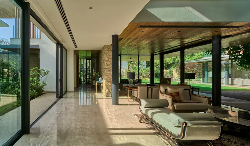 Interior corridor with polished stone floor and timber ceiling opening to courtyard garden through full-height glazing
