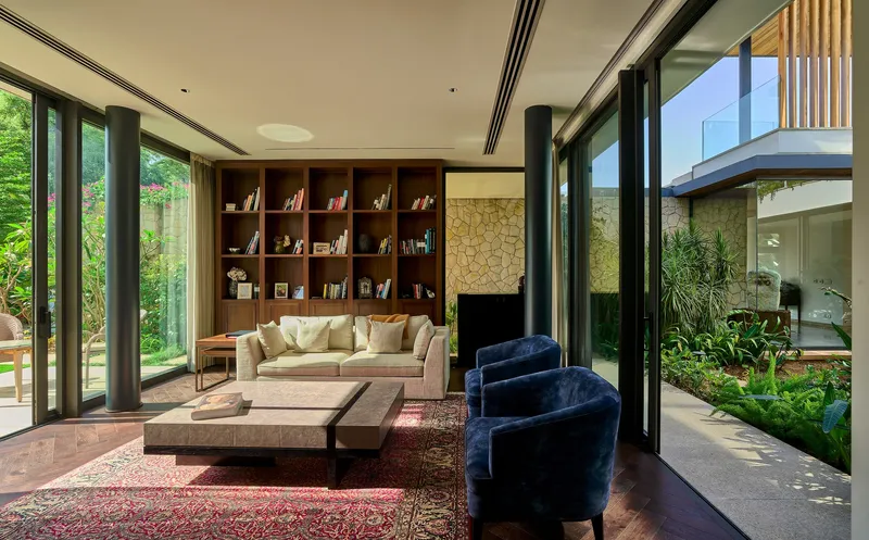 Living area with timber bookshelf wall and sliding glass doors opening to planted courtyard