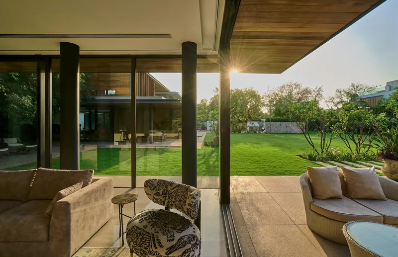 Covered terrace with timber ceiling and steel columns at dusk overlooking lawn and pool