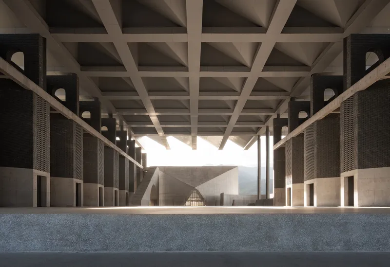 Interior colonnade with coffered ceiling and perforated brick screens filtering natural light into the corridor