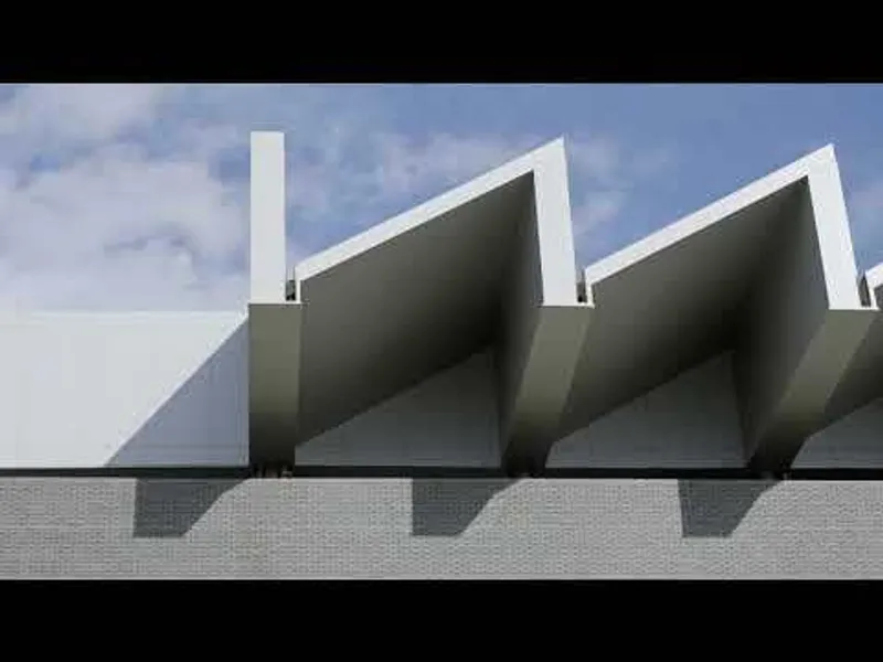 Close view of three sawtooth concrete roof elements against a cloudy sky