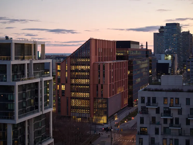 Corner view of the vertical copper cladding and recessed glazing lit from within at twilight
