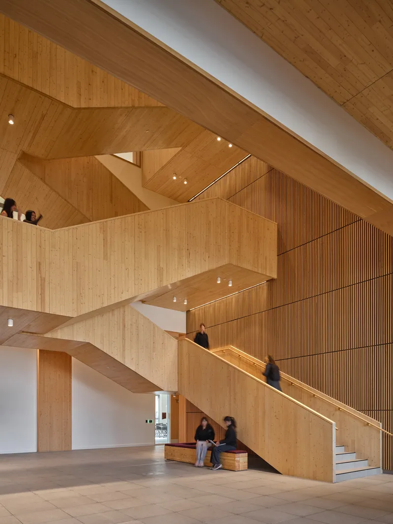 Interlocking timber stairs with vertical slat screen and visitors on multiple landing levels