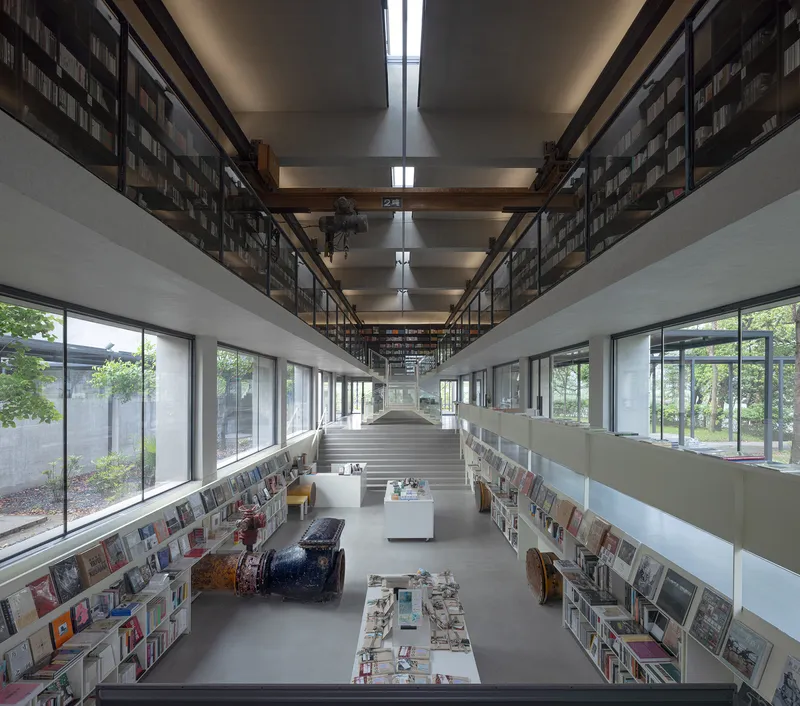 Double-height library interior with central staircase flanked by bookshelves and courtyard windows on both sides