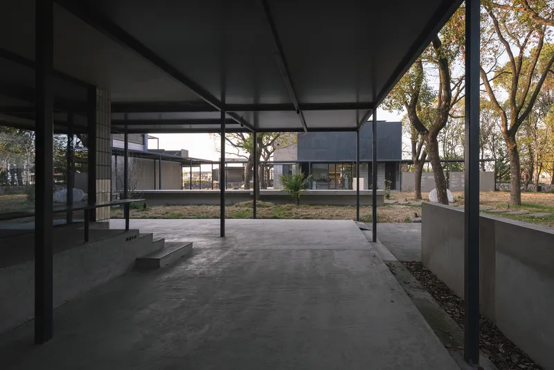 Covered courtyard connecting pavilions with exposed steel frame and planted beds under morning light