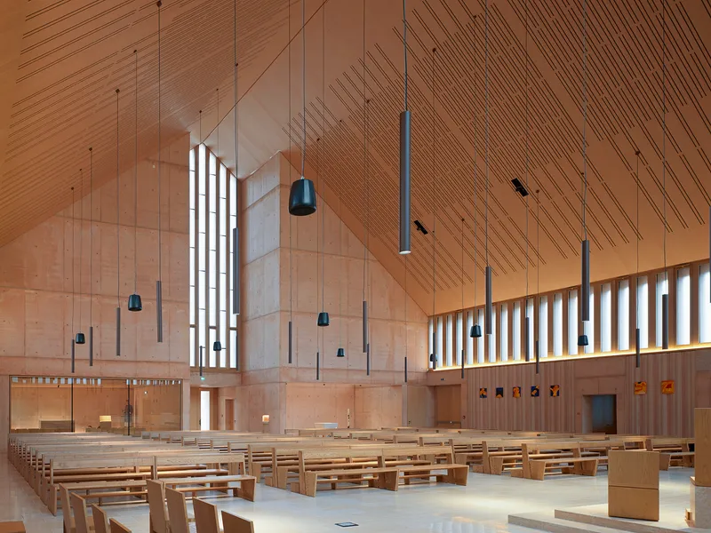 Interior sanctuary with timber ceiling, vertical light slots, suspended pendants and rows of wooden pews