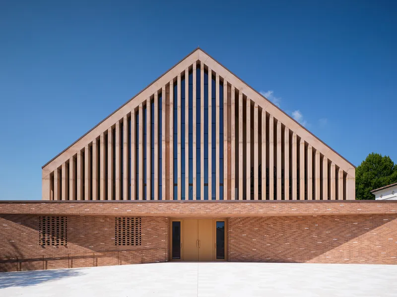 Front elevation showing vertical timber screens framing the entrance doors in a brick facade
