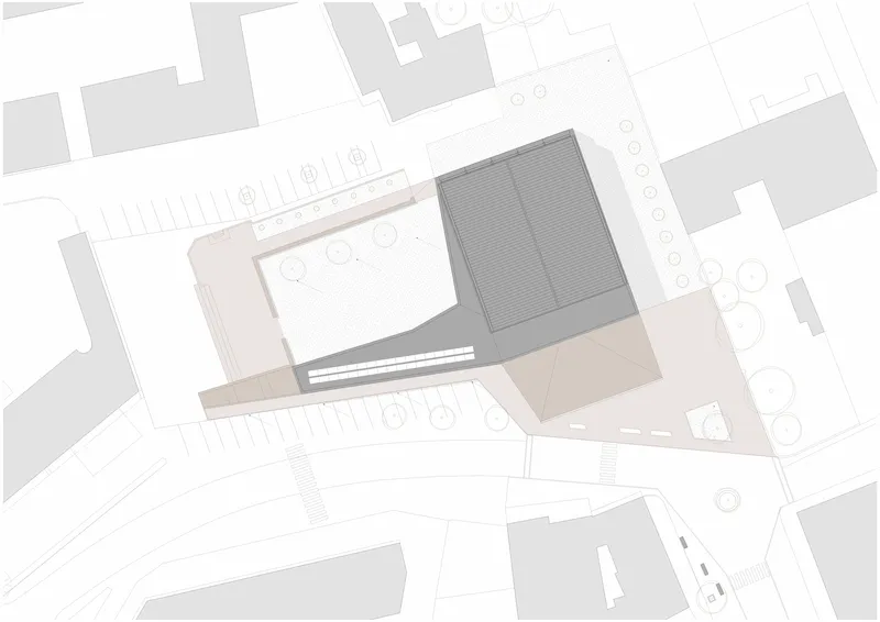 Site plan drawing showing the building footprint with two rectangular volumes and surrounding landscaping and streets