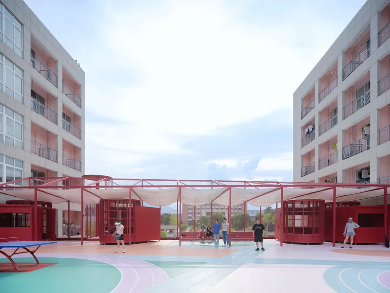 Courtyard with red steel canopy structure and modular volumes between residential blocks with children playing