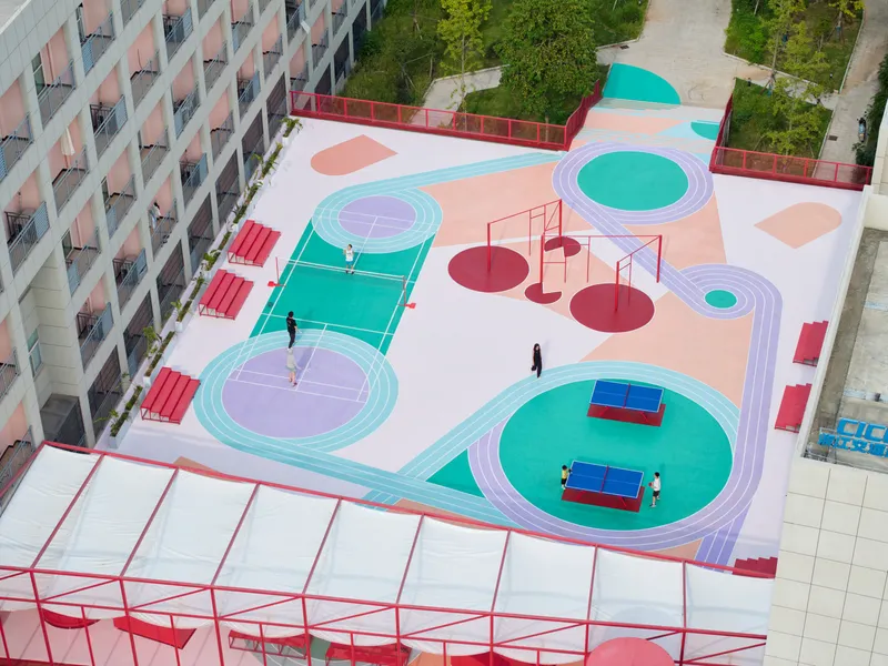Rooftop sports court with concentric painted circles in turquoise and pink and people playing below