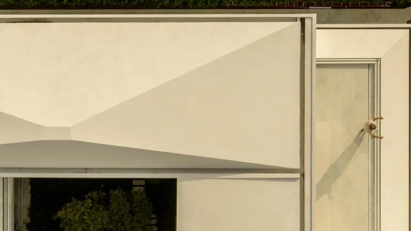 Close-up of the white stucco facade showing the curved roof edge and recessed metal conduit