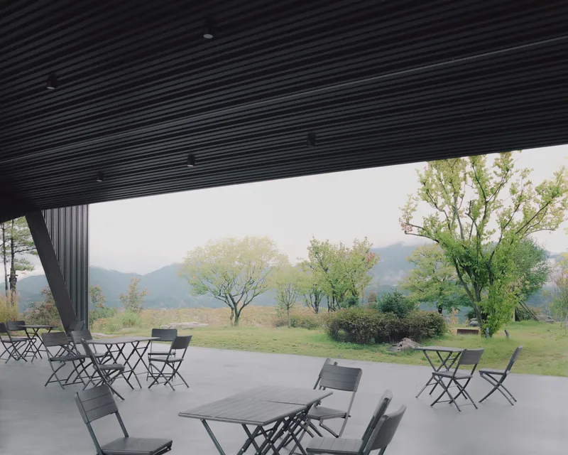 View from beneath the canopy toward scattered seating and a misty landscape with trees