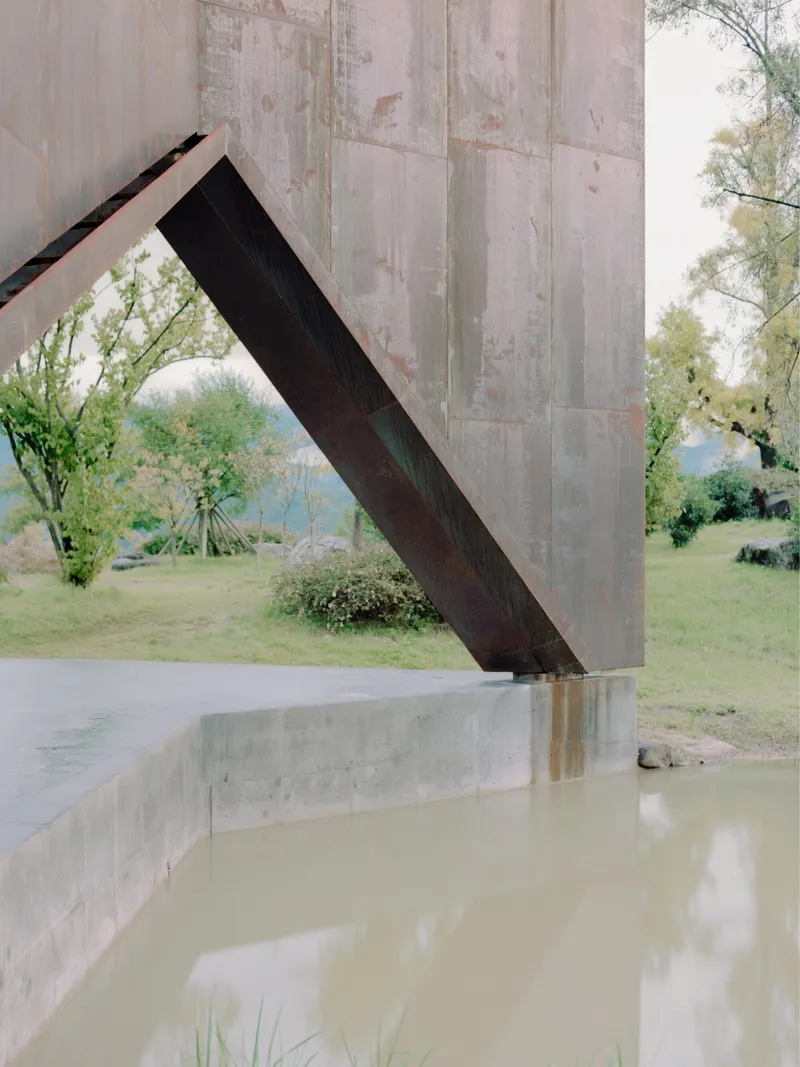 Angled steel brace connecting board-formed concrete column to ceiling near a reflecting pool