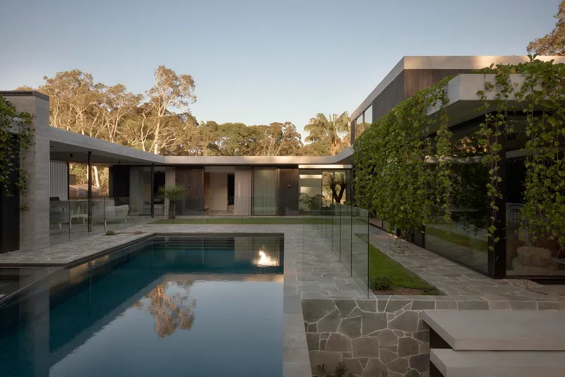 Internal courtyard with rectangular lap pool and frameless glass balustrade at dusk