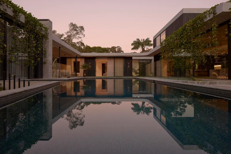 Courtyard pool reflecting glass pavilions and greenery at twilight