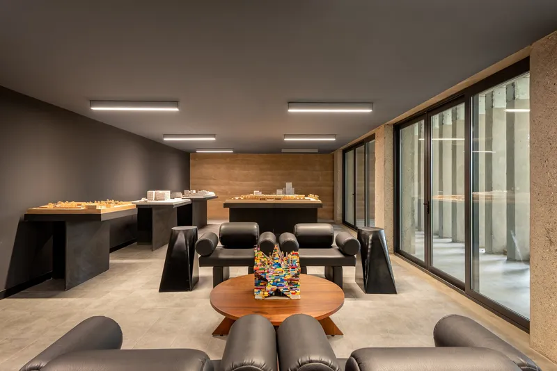 Studio workspace with model tables and lounge seating overlooking a glazed courtyard with vertical fins