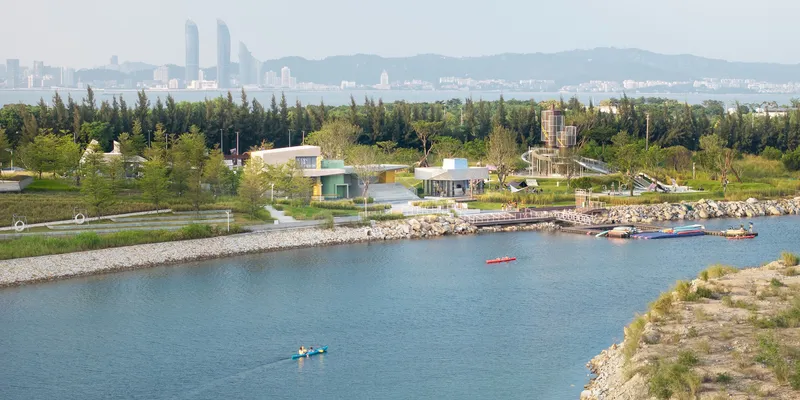 Aerial view of the lakeside complex with recreational watercraft and forested shoreline beyond