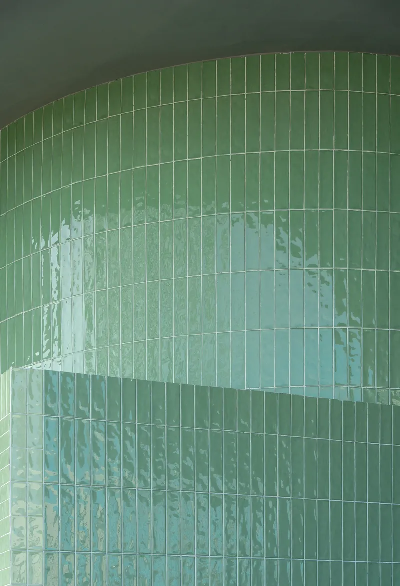 Close-up of the curved green glass block wall with horizontal mortar joints