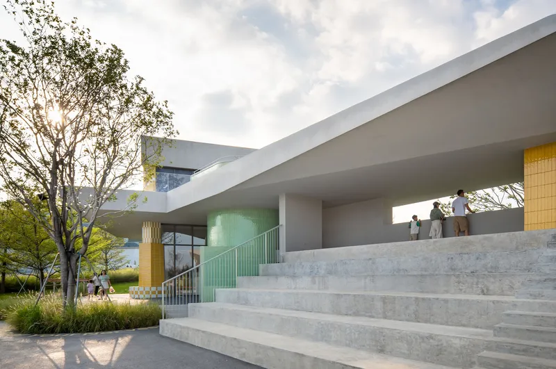 Wide concrete staircase ascending beneath a cantilevered soffit with visitors gathered above
