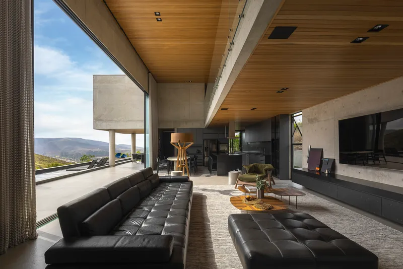 Living room with timber ceiling and floor-to-ceiling glass overlooking distant mountain landscape