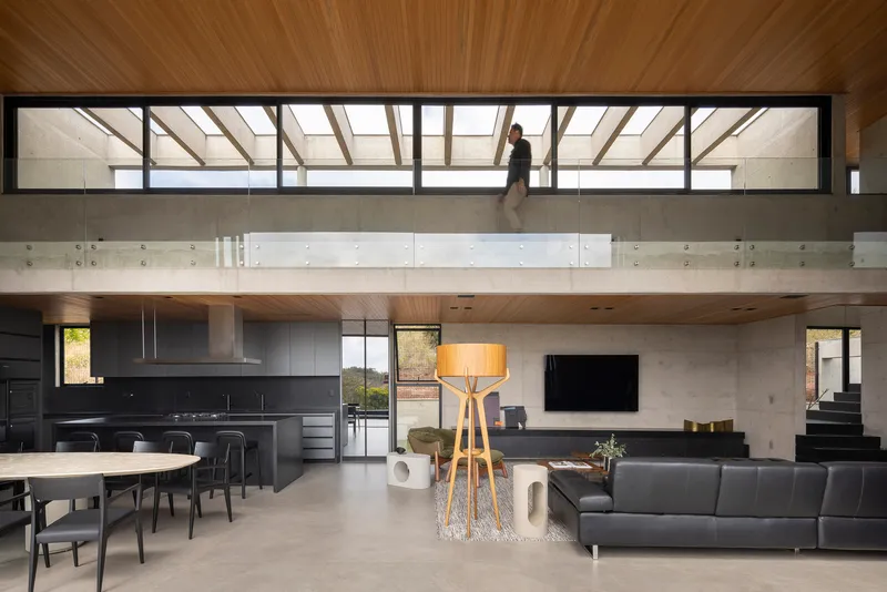 Open living area with mezzanine bridge and clerestory glazing above concrete walls