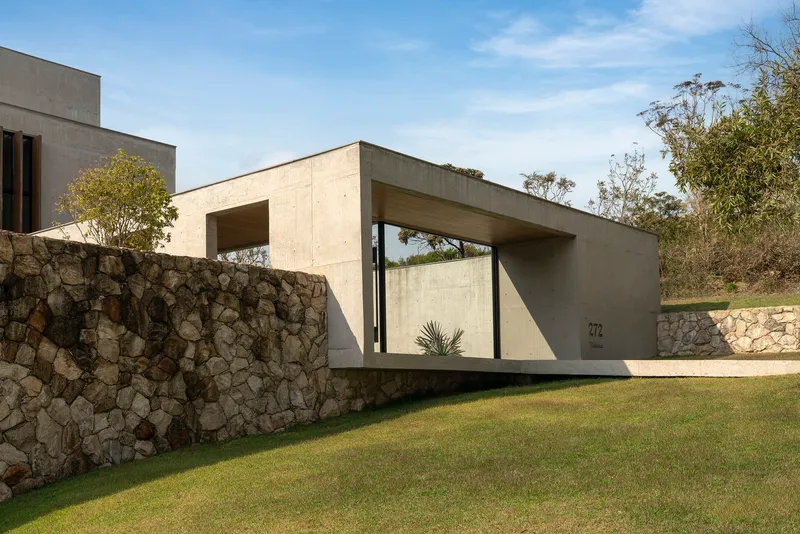Street view of the concrete entry portal with stone gabion wall and lawn in afternoon light