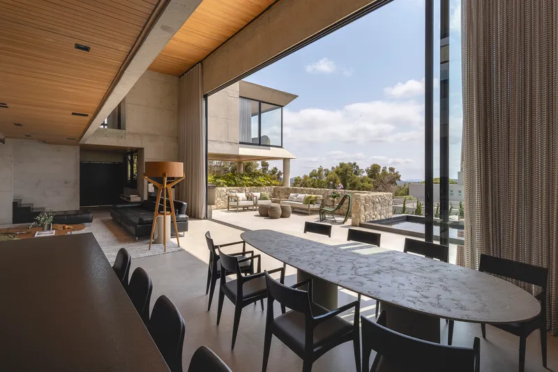 Dining area with marble table extending toward the outdoor terrace and pool