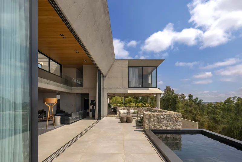 Terrace with stone wall, reflecting pool, and cantilevered volumes under blue sky