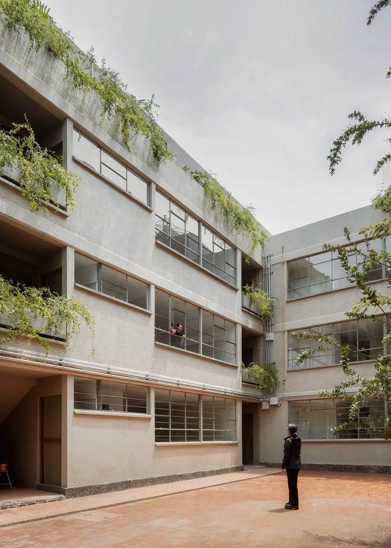 Courtyard view of the concrete facades with ribbon windows and cascading vegetation from rooftop planters