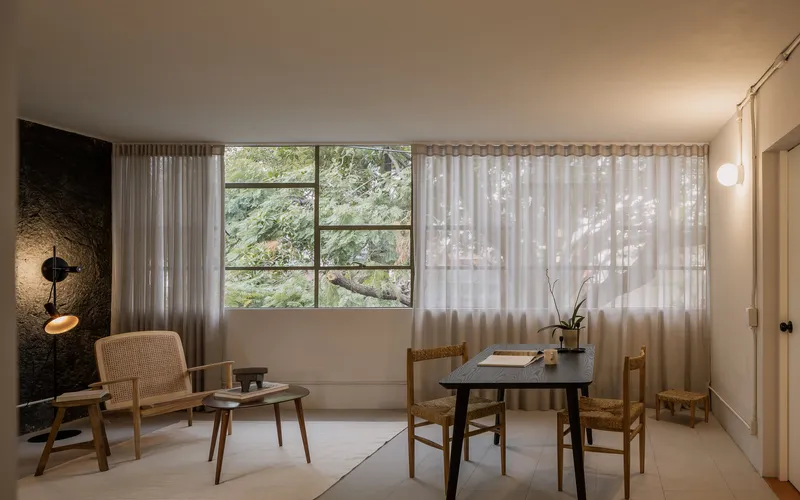 Interior living space with sheer curtains filtering daylight through the gridded metal window frame