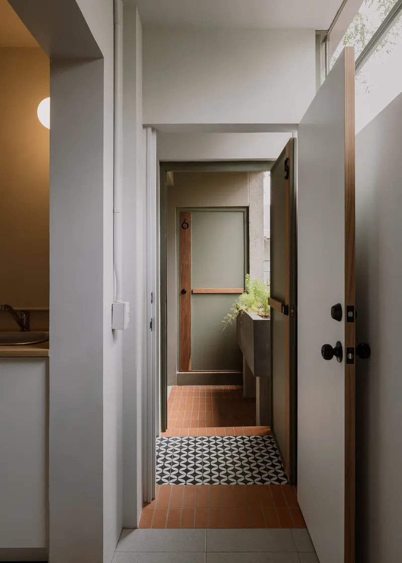 Hallway view through multiple doorways revealing terracotta tile floor and geometric patterned threshold