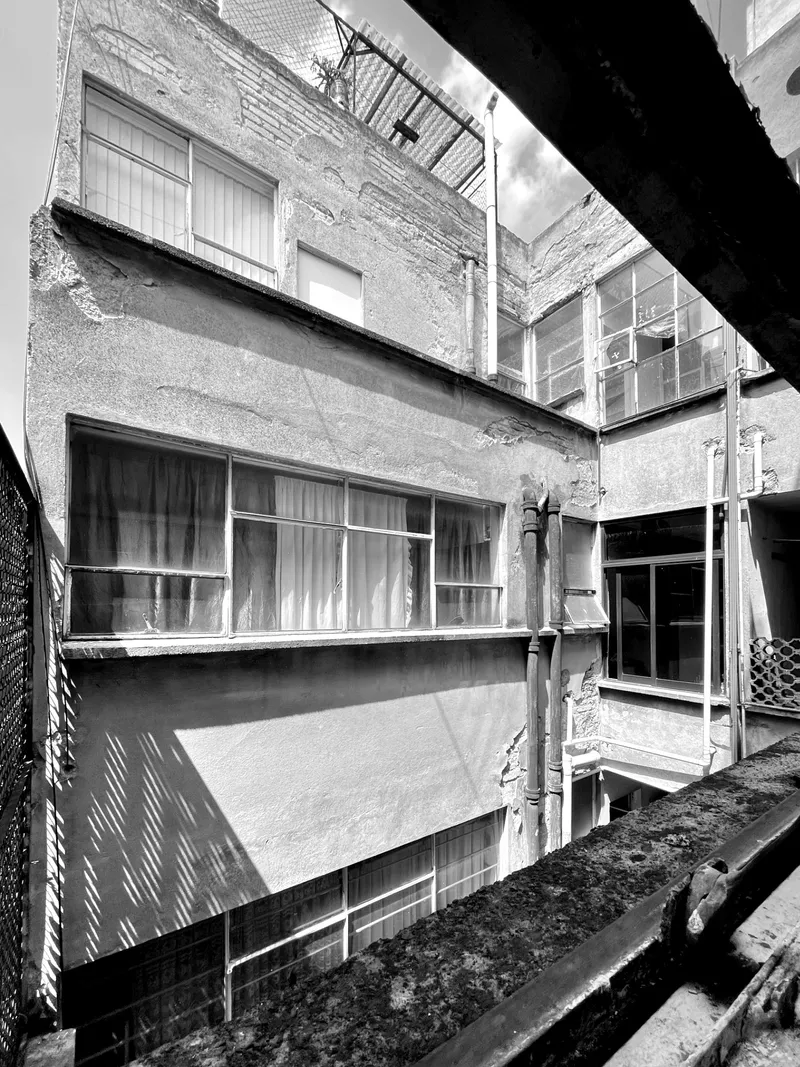 Interior courtyard view showing stacked balconies and ribbon windows in harsh daylight
