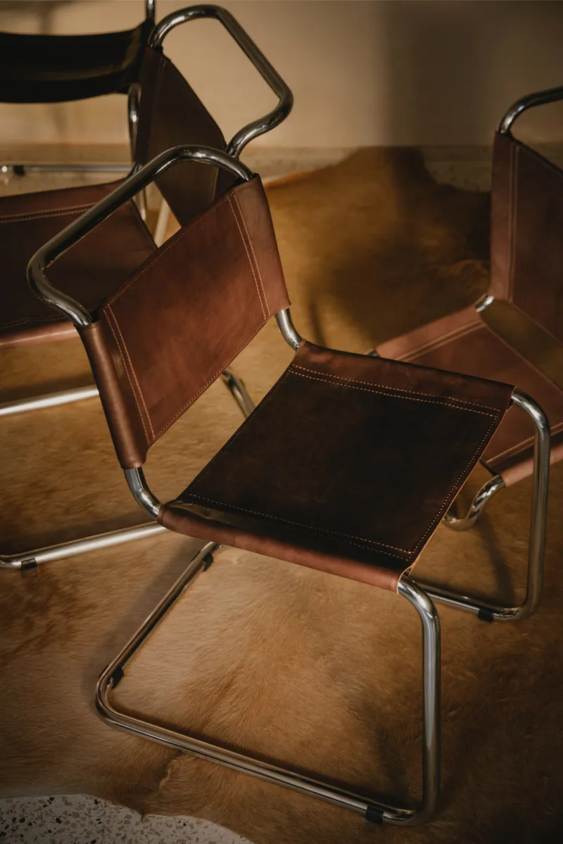Leather and chrome cantilever chairs casting afternoon shadows across timber flooring
