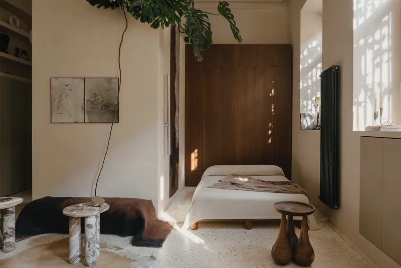 Sleeping area with low platform bed against vertical timber paneling and dappled afternoon sunlight