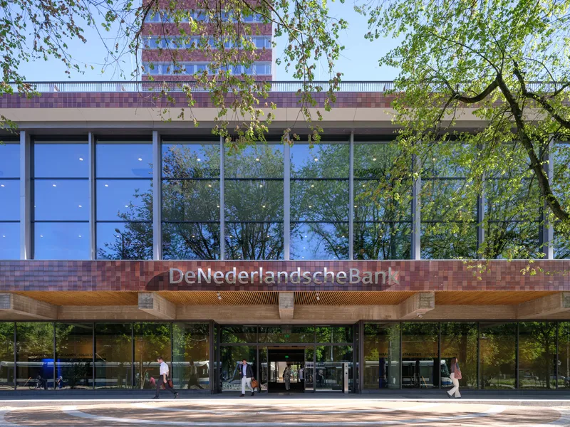 Glass curtain wall entrance with overhanging timber soffit and pedestrians passing under trees