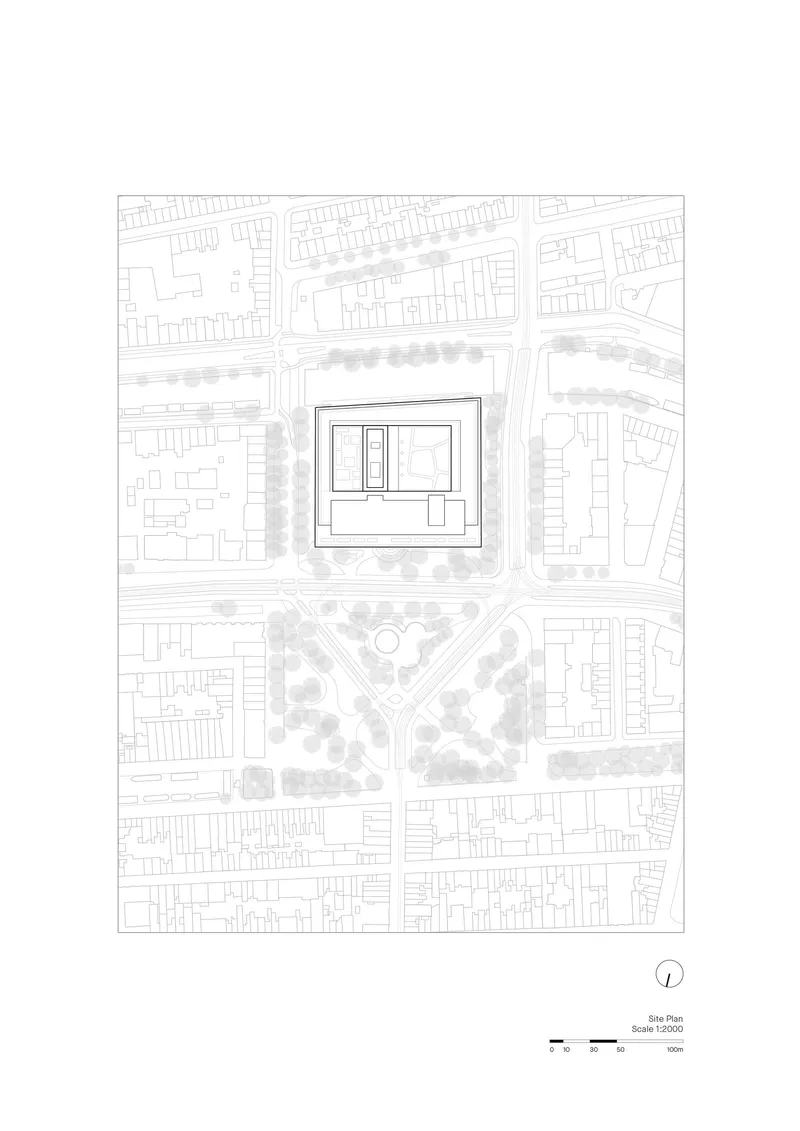 Site plan drawing showing a rectangular building within surrounding urban fabric and tree rows