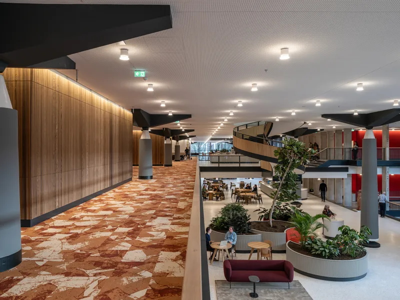 View across a mezzanine with terrazzo flooring showing the curved timber wall and atrium below