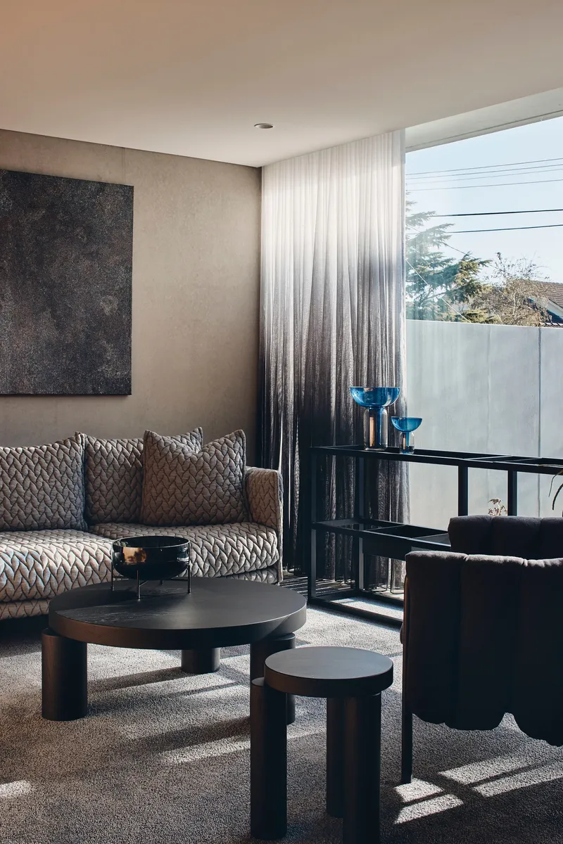 Living room with gradient curtains and floor-to-ceiling window overlooking trees and concrete wall