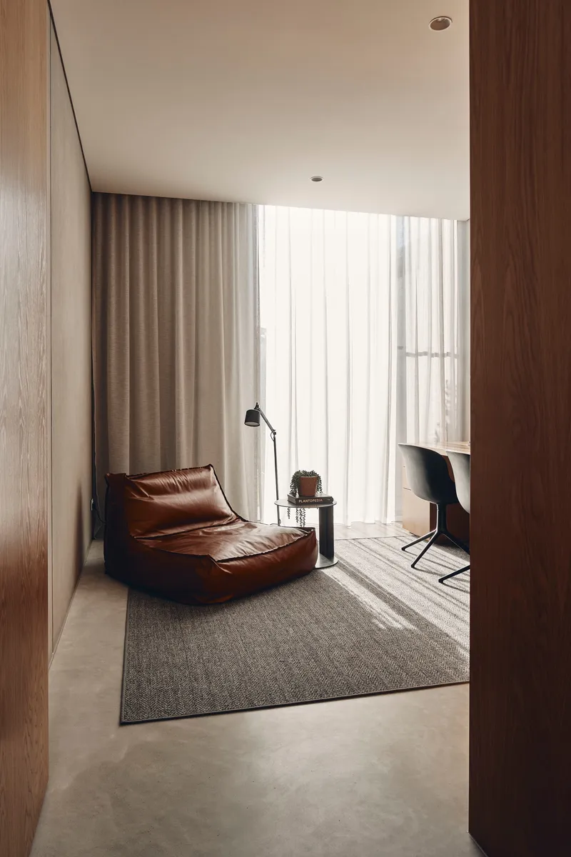Corridor view through timber-clad doorway to sitting area with leather lounge and sheer curtains