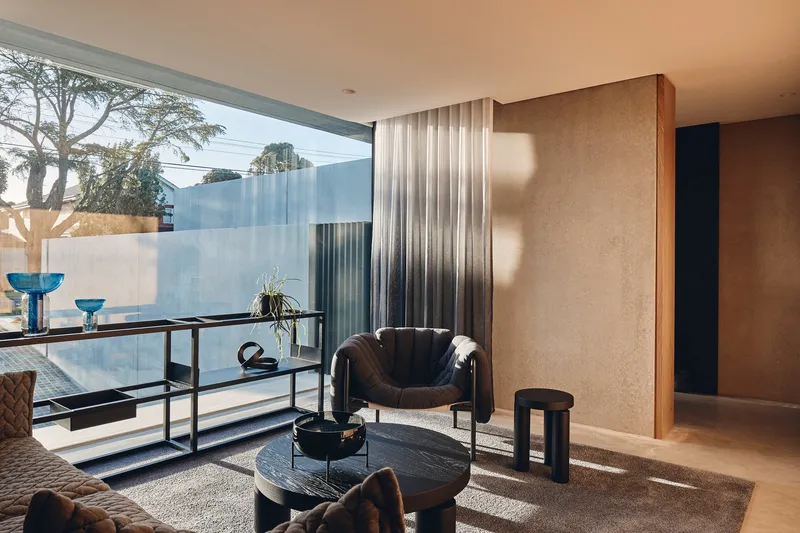 Corner window with metal console table and glassware overlooking frosted courtyard walls in afternoon light