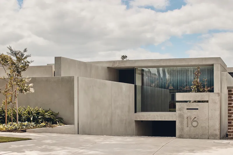 Recessed entry portal in the concrete facade with horizontal glazing and a cast address number