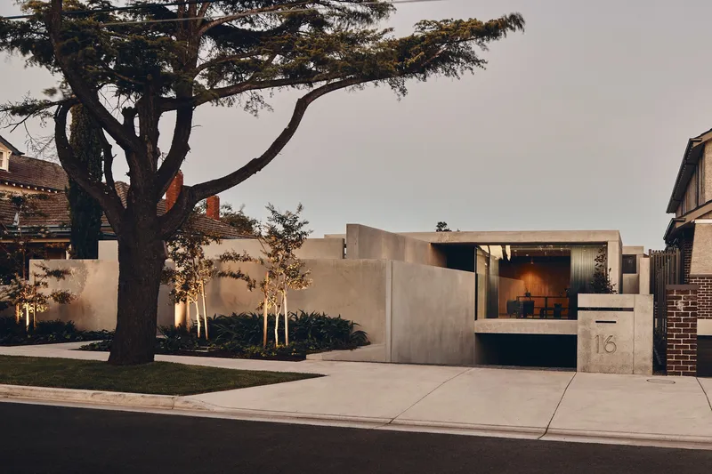 Street view of the concrete wall and recessed entry beneath a broad canopy at dusk