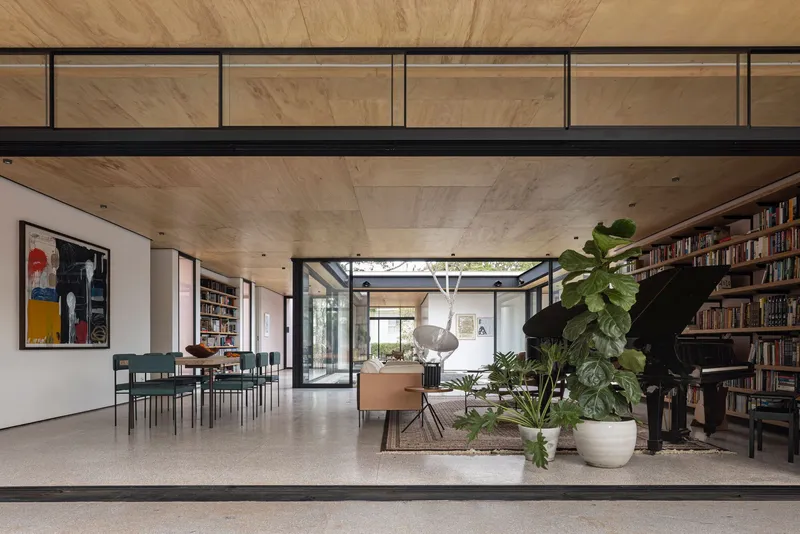 Open-plan living space with timber-clad ceiling and clerestory glazing overlooking the planted courtyard