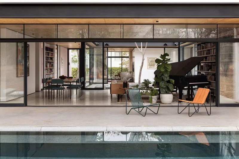 Fully open steel-framed glazed wall revealing the interior living space and reflecting pool beyond