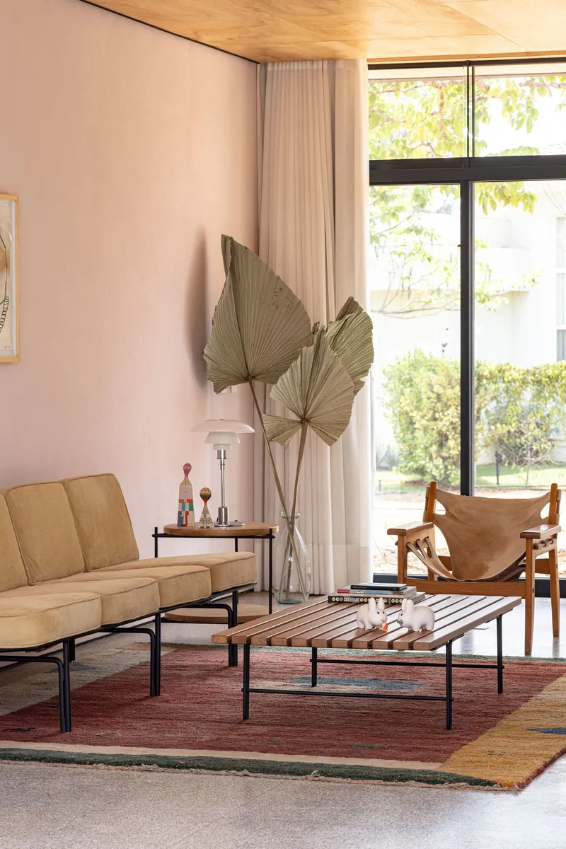 Living room with floor-to-ceiling glazing, timber ceiling and sheer curtains filtering afternoon light