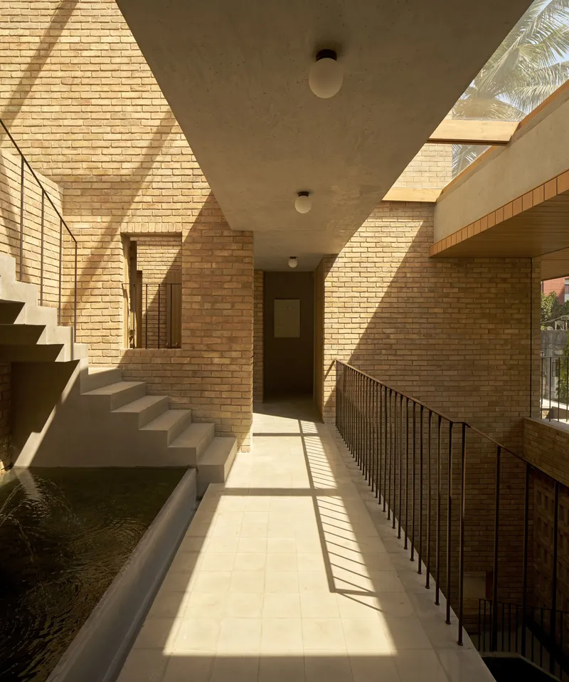 Upper corridor with perforated brick walls casting geometric shadows across the concrete ceiling