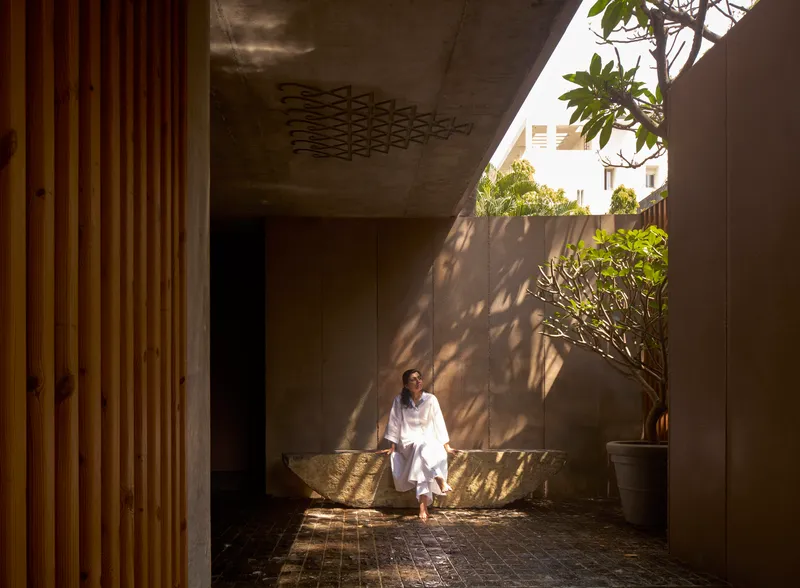 Ground floor courtyard with concrete soffit featuring geometric pattern and person seated on stone bench